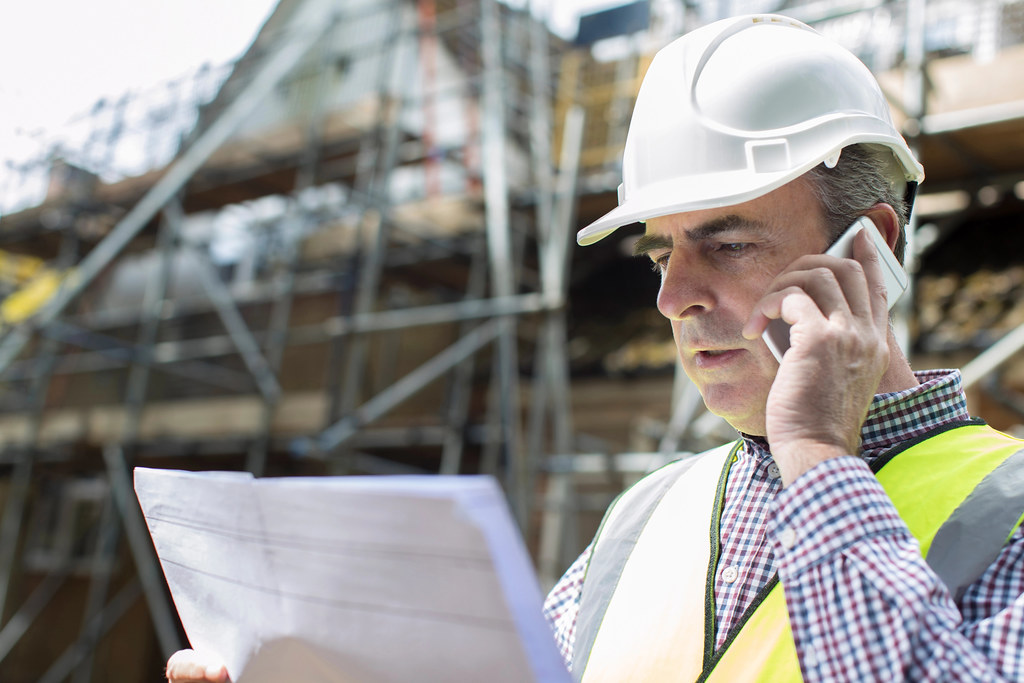 Architect on construction site with mobile phone